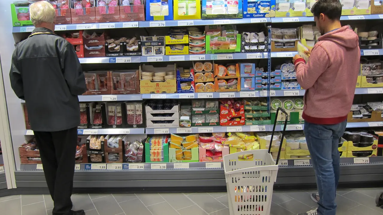 Dos hombres ante el expositor de una supermercado. / E.P.