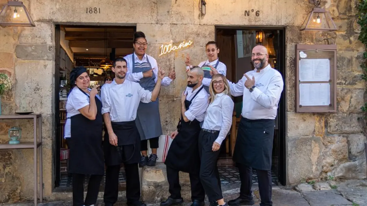 El equipo del restaurante Pasaje de los Nobles a la puerta del establecimiento mostrando el ne&oacute;n luminoso instalado con motivo de centenario, en manos de la cuarta generaci&oacute;n de la misma familia, una historia de la que habla con EFE Bel&eacute;n Morquillas, al frente ahora del restaurante.-EFE/Javier G. Paradelo