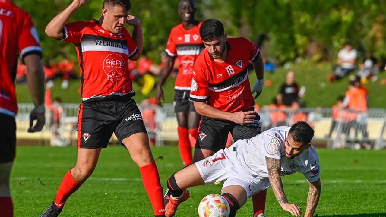 El delantero del Sevilla FC, Jes&uacute;s Fern&aacute;ndez Suso (c), disputa un bal&oacute;n a los jugadores del Velarde CF durante el partido de la Copa del Rey, este domingo, en las instalaciones deportivas municipales de La Maruca en la localidad c&aacute;ntabra de Malia&ntilde;o. EFE/Pedro Puente Hoyos