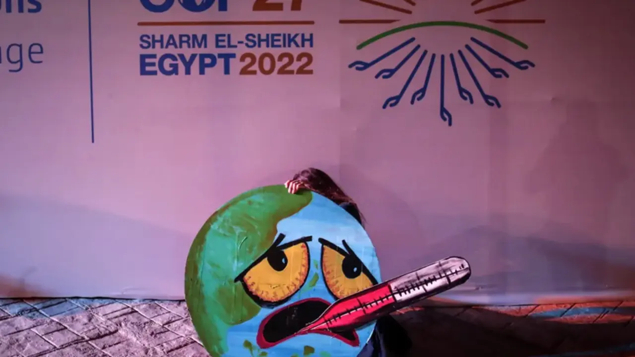 Una activista sostiene una imagen de la Tierra representada como una cara enferma, en la COP27 de Sharm El-Sheikh, Egipto. EFE/EPA/Sedat Suna