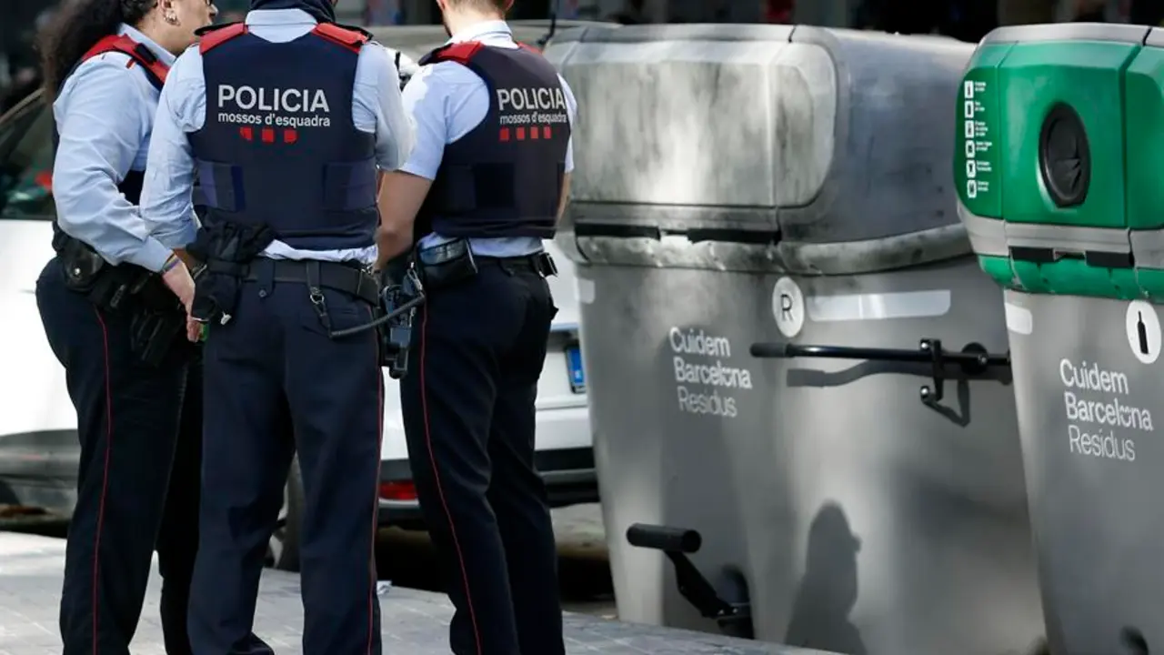 Tres mossos permanecen junto al contenedor donde esta ma&ntilde;ana se ha encontrado el cad&aacute;ver mutilado de una persona dentro de una maleta en el barrio de L'Eixample de Barcelona. EFE/Andreu Dalmau