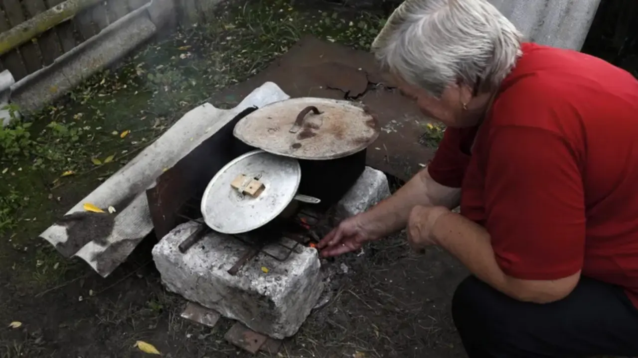Una mujer prepara la comida en un horno de piedra en una aldea de Ucrania. EFE/EPA