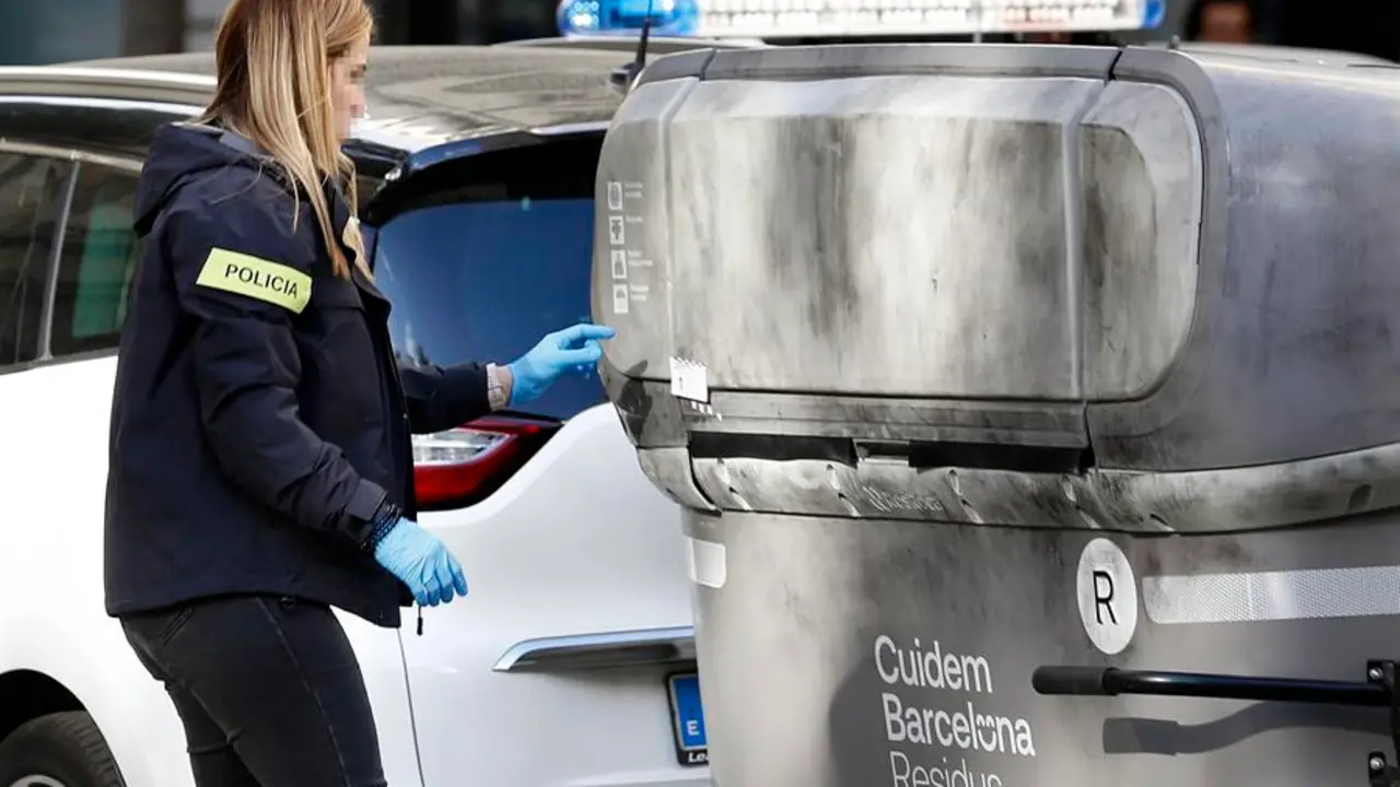 Una agente de los Mossos d'Esquadra realiza su trabajo en la calle Casanova con Avenida de Roma donde un vecino ha hallado el cad&aacute;ver mutilado de una persona dentro de una maleta en un contenedor (i). EFE / Andreu Dalmau