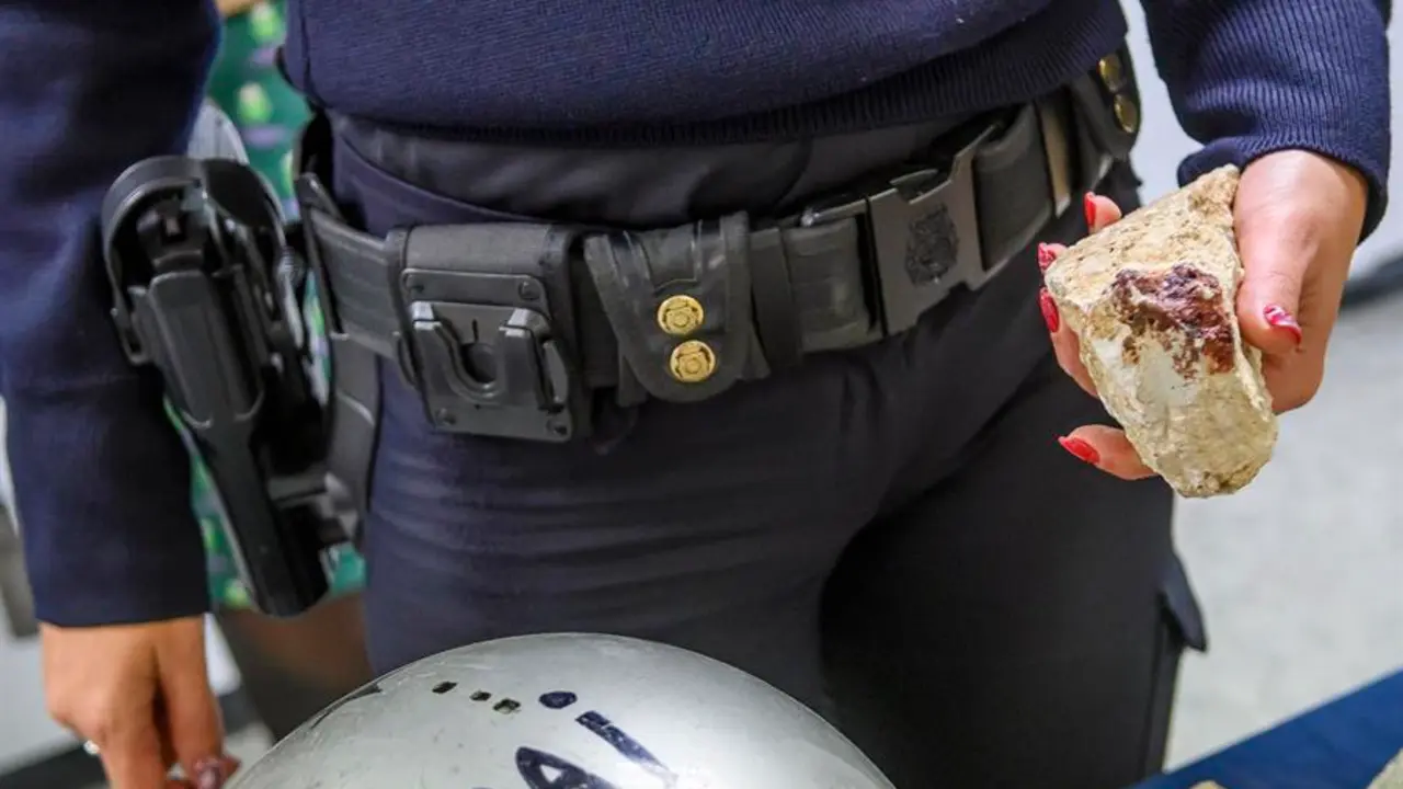 Una agente de la Polic&iacute;a Nacional muestra un piedra usada en un enfrentamiento entre grupos ultras del Sevilla F.C. y del Real Betis Balompi&eacute;. EFE / Ra&uacute;l Caro