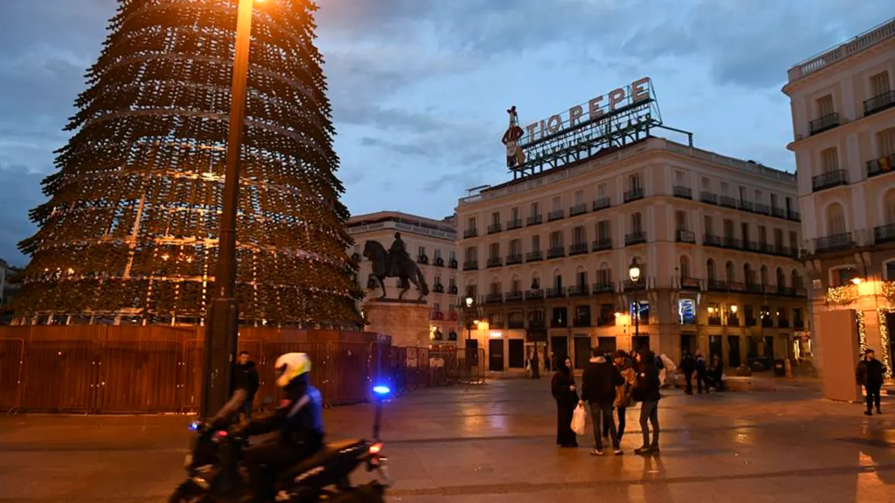 Un efectivo de la Polic&iacute;a Local pasa junto a un grupo de personas a primera hora de este domingo, 1 de enero de 2023. EFE / V&iacute;ctor Lerena