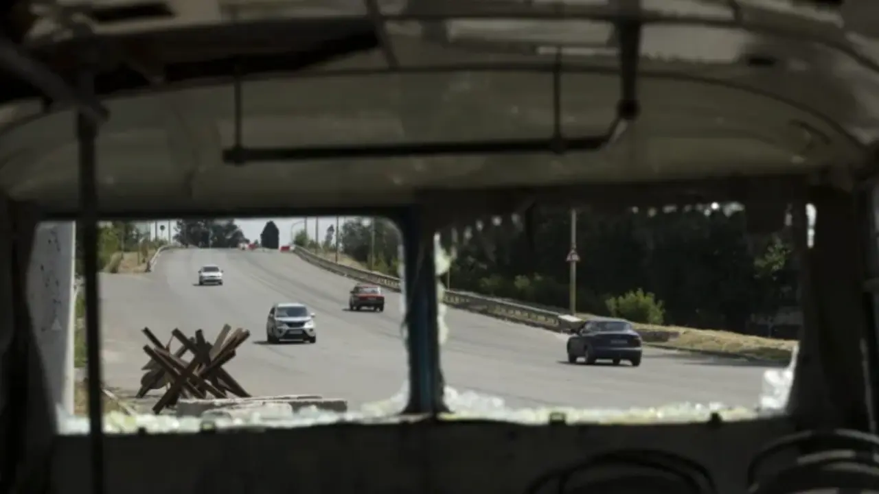 Autom&oacute;viles pasan junto a un autob&uacute;s destruido a un costado de la carretera que conduce a Dnipro (Ucrania). EFE / Orlando Barr&iacute;a