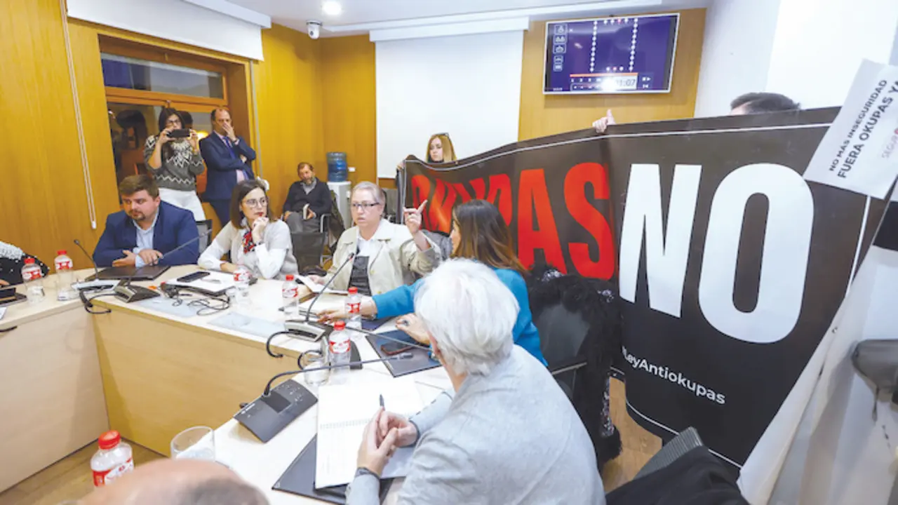 Una imagen del &uacute;ltimo pleno celebrado en el Ayuntamiento de Torrelavega, donde la presidenta del movimiento &lsquo;Meruelo sin okupas&rsquo; y coordinadora a nivel nacional de la plataforma &lsquo;Mi barrio seguro&rsquo;, Noem&iacute; Mu&ntilde;oz, detallaba los datos &laquo;abrumadores&raquo; de los casos en Torrelavega y Cantabria, que siguen en aumento. Sujetando el cartel al fondo, Elina Villegas. / ALERTA