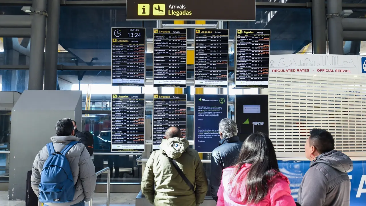 Varias personas observan los paneles informativos que anuncian retrasos de llegadas en algunos vuelos de Iberia en la Terminal 4 del Aeropuerto Madrid-Barajas Adolfo Su&aacute;rez. E.P. / Gustavo Valiente