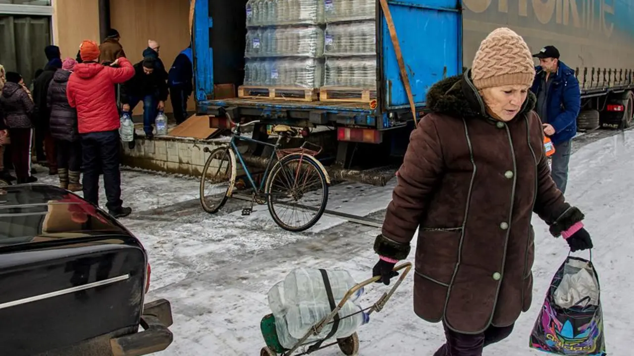 Una mujer recoge agua que se entrega de manera gratuita a los residentes de Oleksandro-Kalynove, en el este de Ucrania. / SERGEY KOZLOV