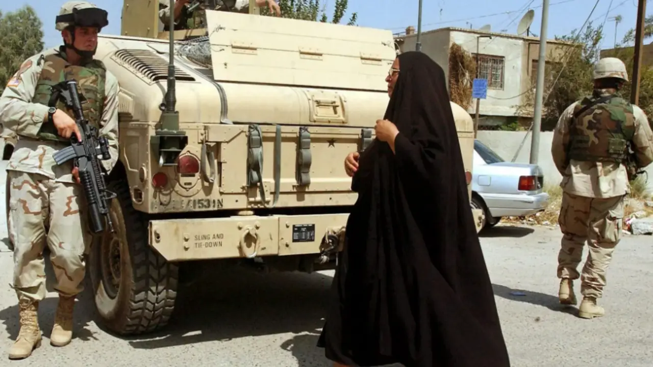 Fotograf&iacute;a fechada el 8 de septiembre de 2004 que muestra a una mujer iraqu&iacute; que se cruza con soldados estadounidenses que patrullan las calles de Bagdad (Irak). EFE/Mohammed Messara