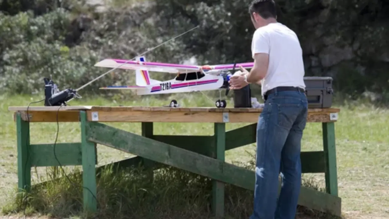 Un hombre junto a un avi&oacute;n de aeromodelismo.