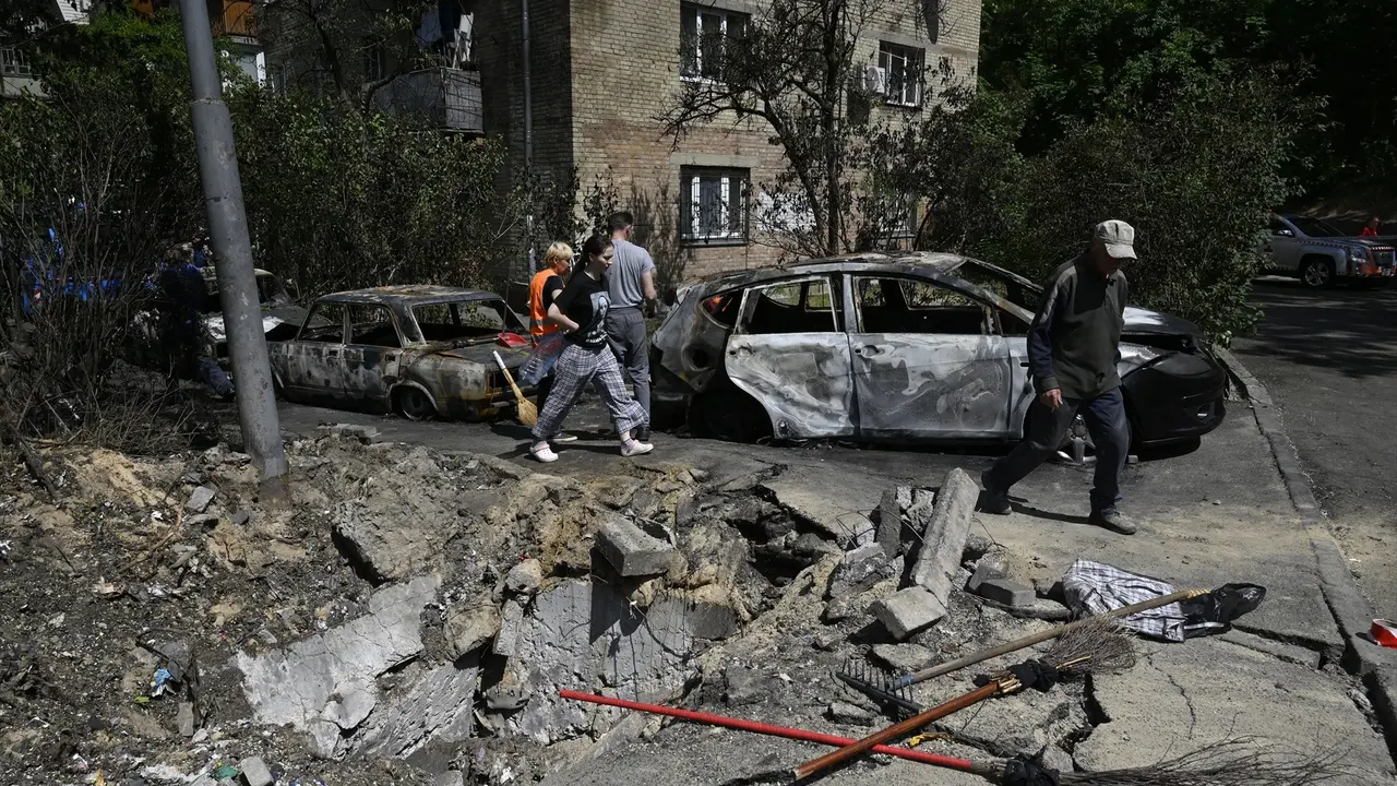 Unas personas caminan junto a dos coches destruidos por la guerra. EP / Sergei Chuzavkov