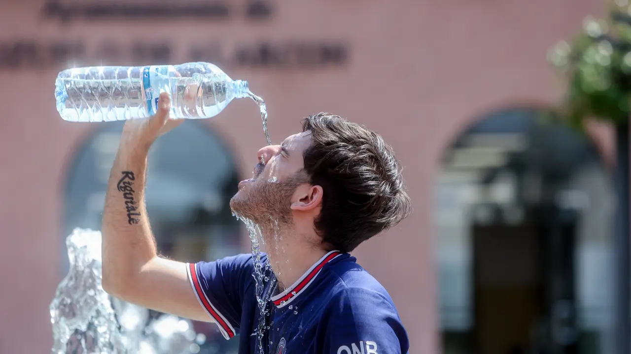 Un joven se tira una botella de agua por encima para combatir el calor del verano. / Ricardo Rubio