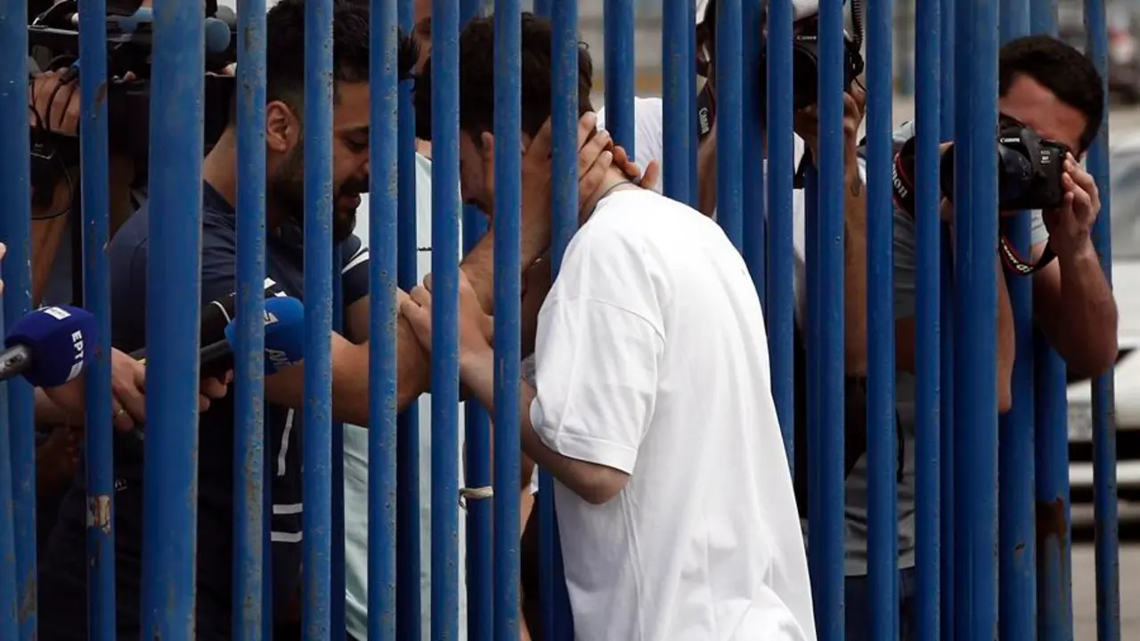Fardi (i) de Siria, abraza a su hermano rescatado Mohamed (d), entre una valla en el puerto de Kalamata, Grecia. EFE / YANNIS KOLESIDIS