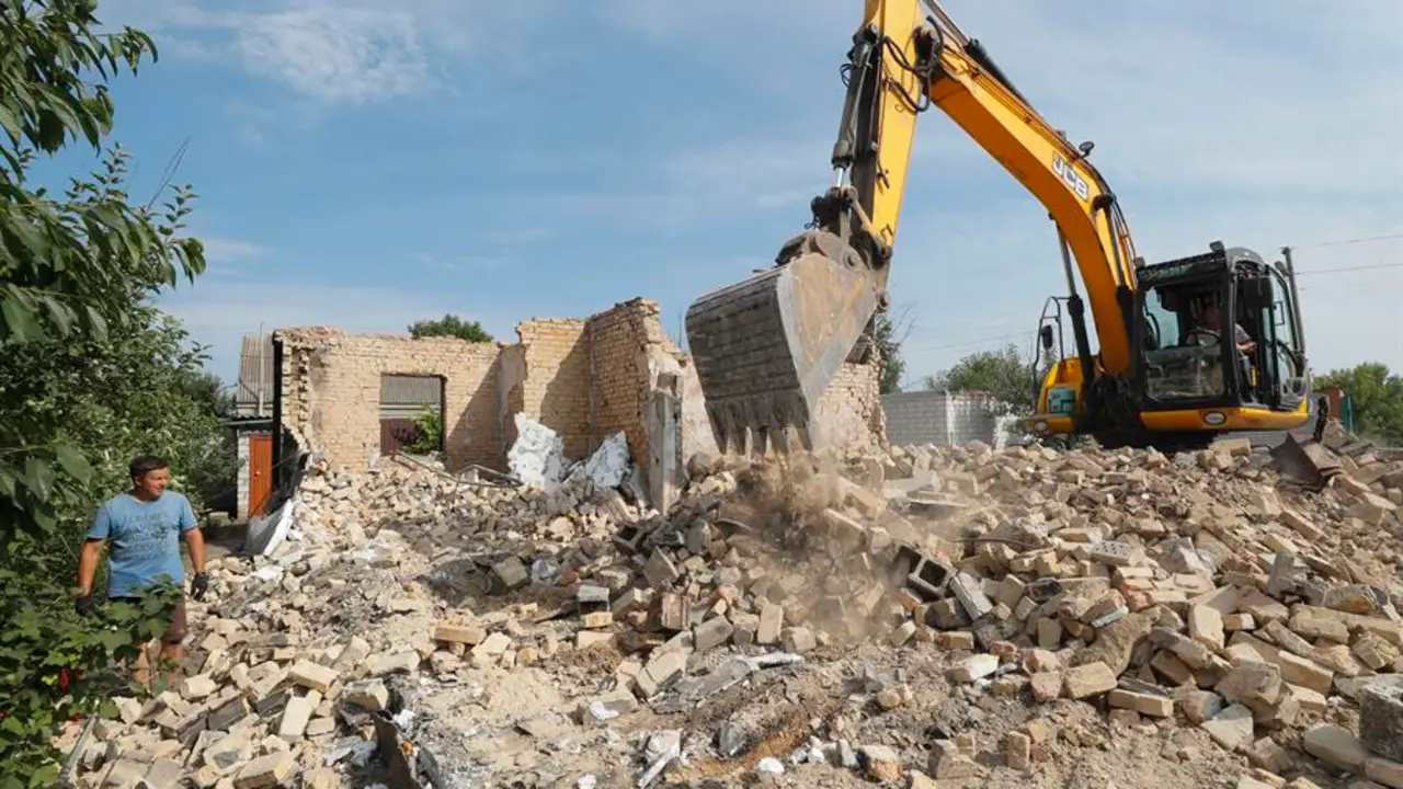 Vecinos trabajan para quitar los escombros de las estructuras destruidas por los bombardeos. EFE / SERGEY DOLZHENKO