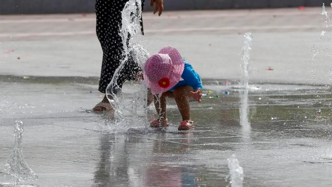 Una ni&ntilde;a se refresca en una fuente de chorros. / J.C. Hidalgo