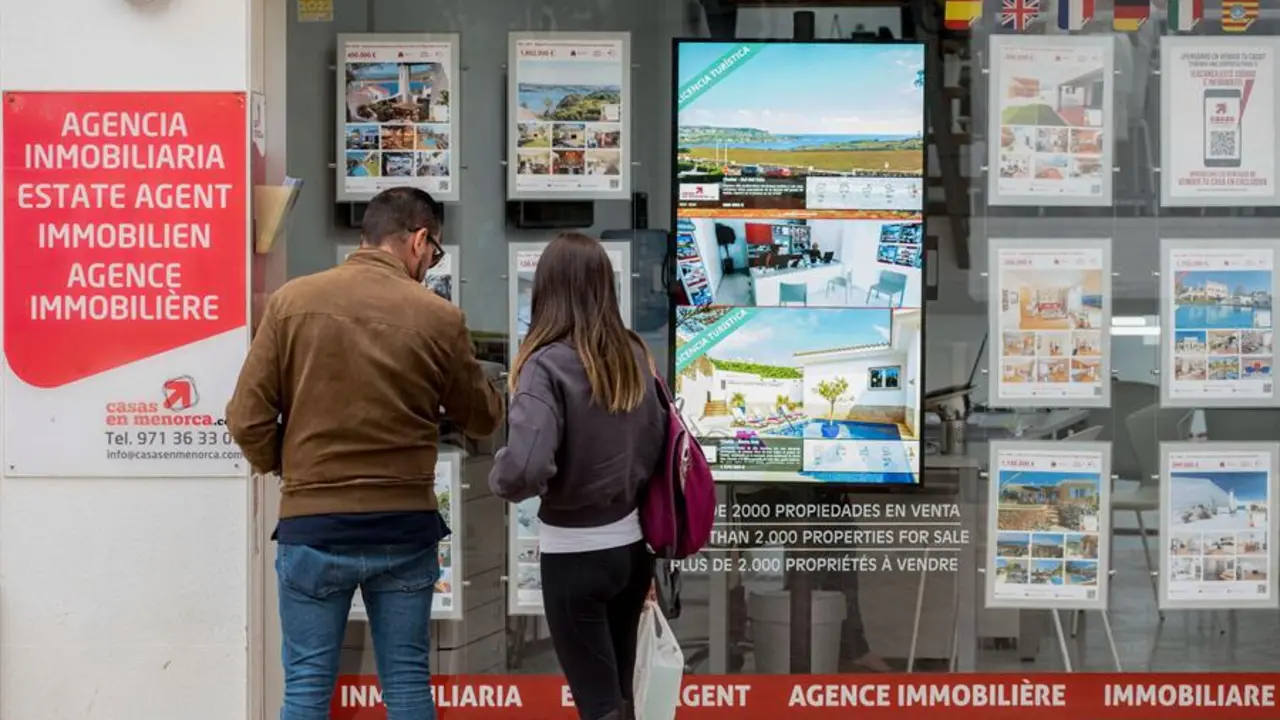 Una pareja se detiene a observar las propiedades en venta anunciadas en el escaparate de una agencia inmobiliaria. EFE / David Arquimbau