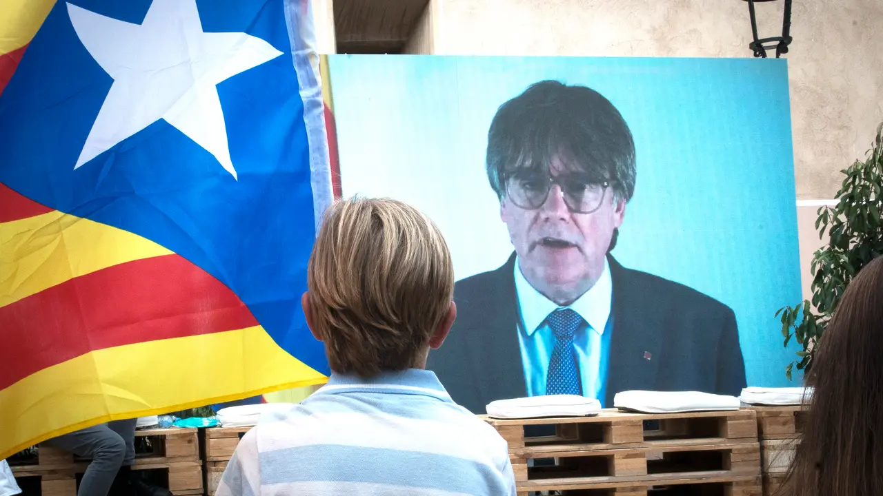 Un niño observa una intervención telemática de Puigdemont.  ALERTA
