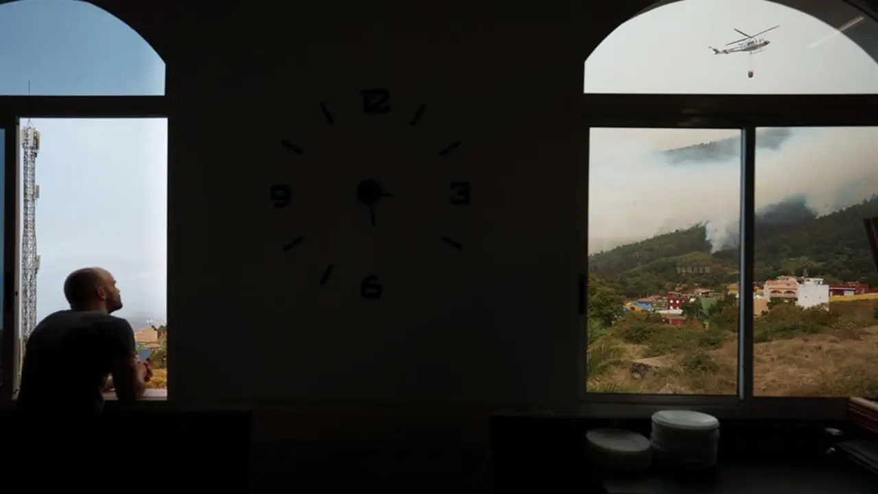 Un hombre observa desde una ventana de un restaurante de Aguamansa, en el municipio de La Orotava, los trabajos de los helic&oacute;pteros que trabajan en la extinci&oacute;n del incendio forestal. EFE / Ram&oacute;n de la Rocha