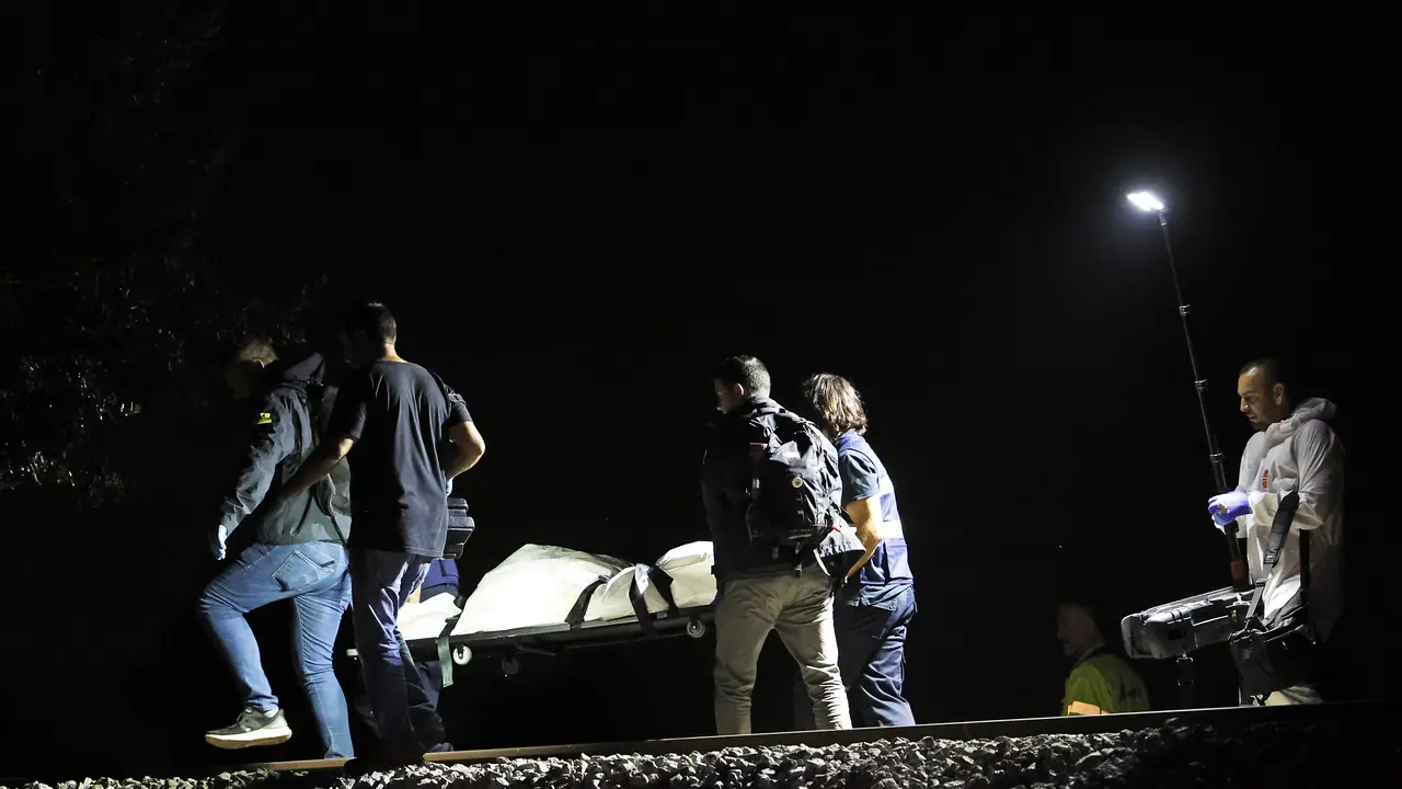 Los operarios retiran el &uacute;ltimo cad&aacute;ver despu&eacute;s de que cuatro j&oacute;venes murieran este domingo por la noche al ser arrollados por un tren a la altura de Montmel&oacute;, en la comarca del Vall&egrave;s Oriental (Barcelona), cuando un grupo de siete personas trataba de cruzar la v&iacute;a por un punto no autorizado. EFE/Alberto Est&eacute;vez
