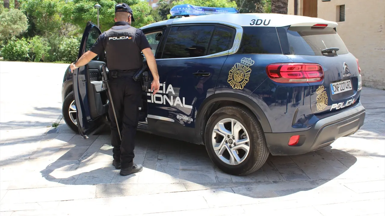 Un agente abriendo la puerta de un coche de la Polic&iacute;a Nacional. EP