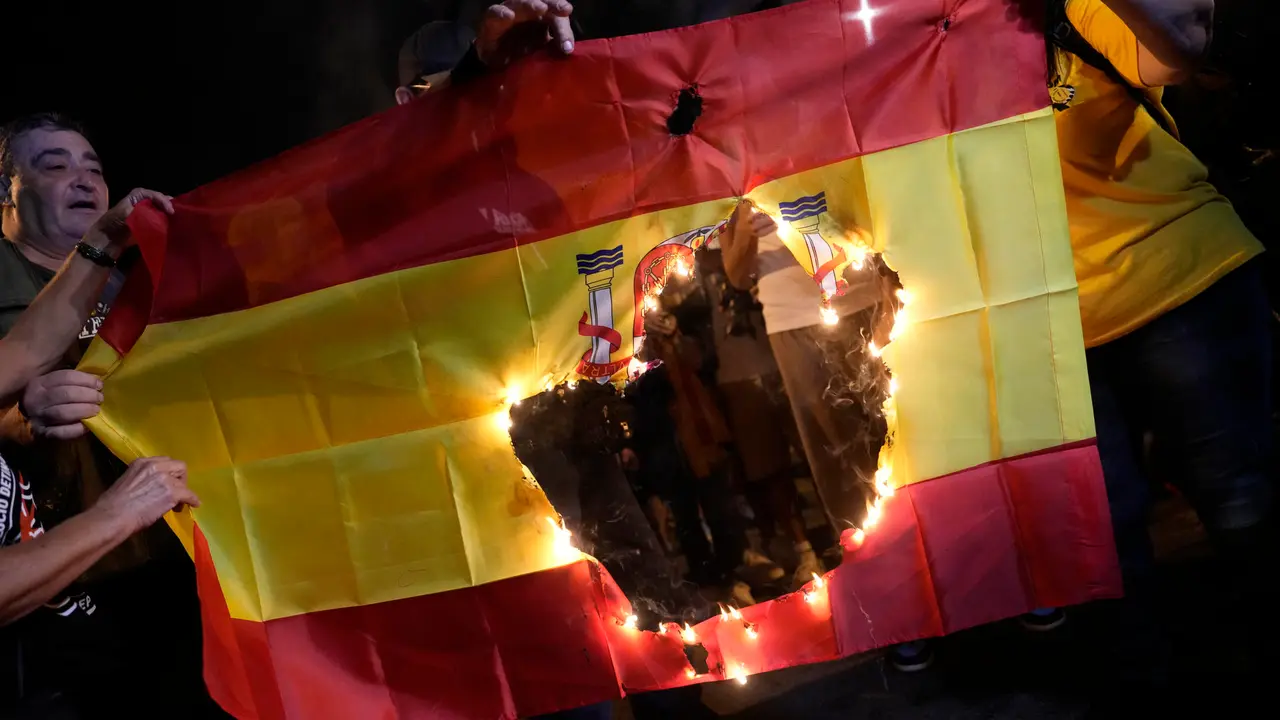 Manifestantes queman una bandera de Espa&ntilde;a durante la concentraci&oacute;n en la que las entidades independentistas. / Enric Fontcuberta