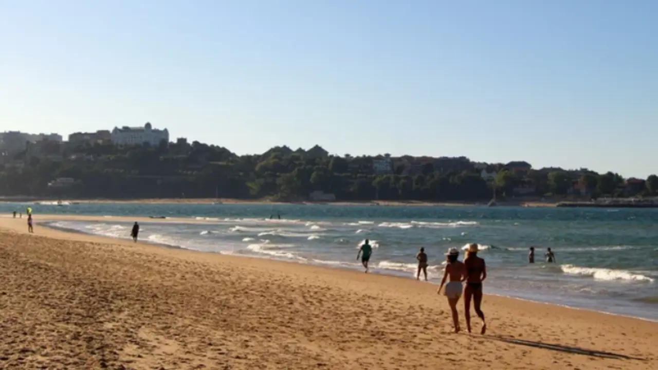 Gente paseando por la playa de Somo en una tarde soleada y ventosa Santander.