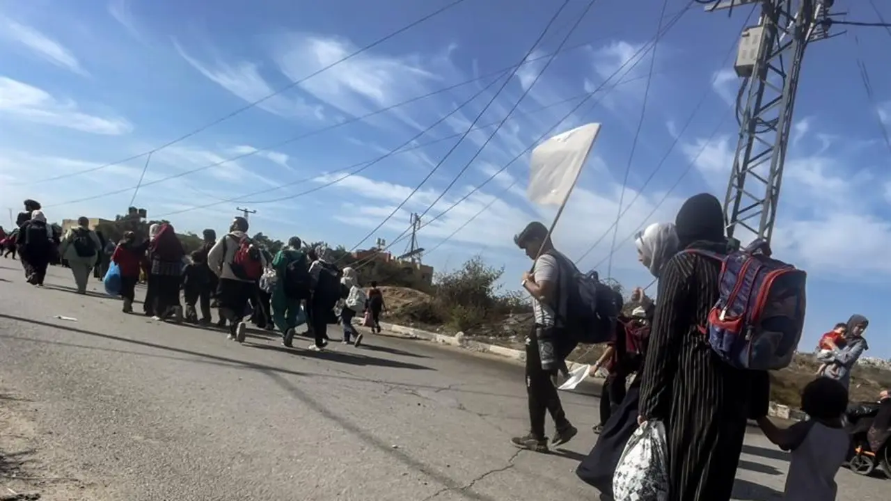 Palestinos, con una bandera blanca improvisada, parten hacia el sur de la Franja de Gaza a trav&eacute;s de un puesto de control del ej&eacute;rcito israel&iacute;. EFE /  MOHAMMED SABRE