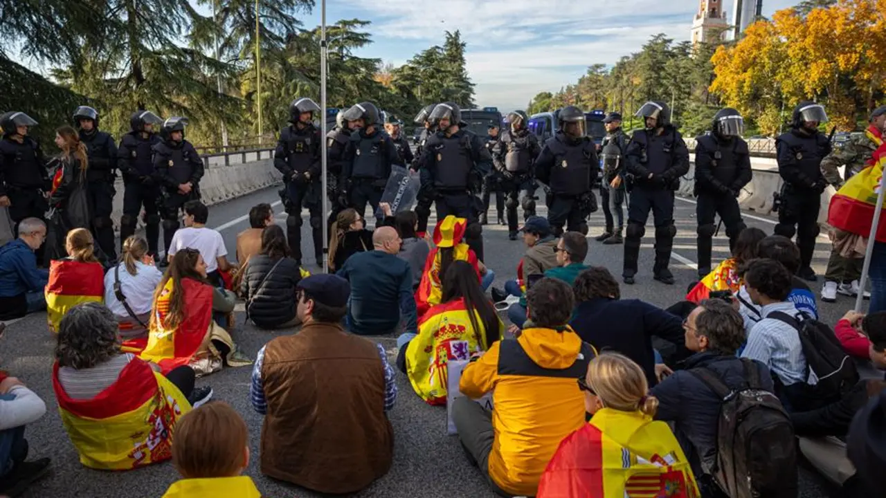 nos j&oacute;venes con banderas y pancartas protagonizan una sentada frente a efectivos de la Polic&iacute;a Nacional durante la manifestaci&oacute;n que han trasladado hasta las inmediaciones de La Moncloa y los accesos de la A-6 a la capital. EFE / Daniel Gonz&aacute;lez