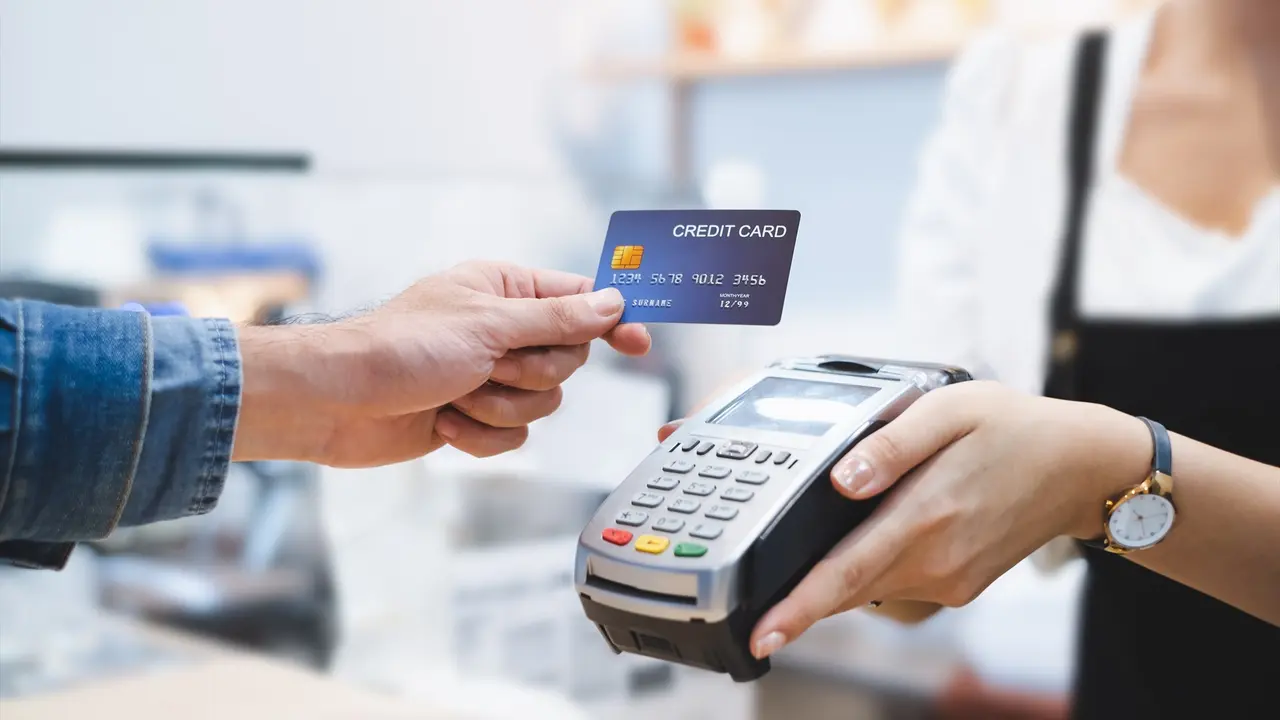 Una persona pagando con tarjeta de cr&eacute;dito en un datafono de un comercio. EP