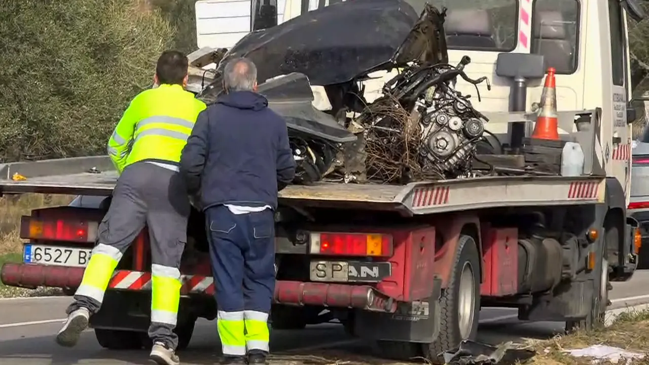 Una gr&uacute;a se lleva restos de un veh&iacute;culo en el que han fallecido tres personas, un adulto y dos adolescentes. / EFE