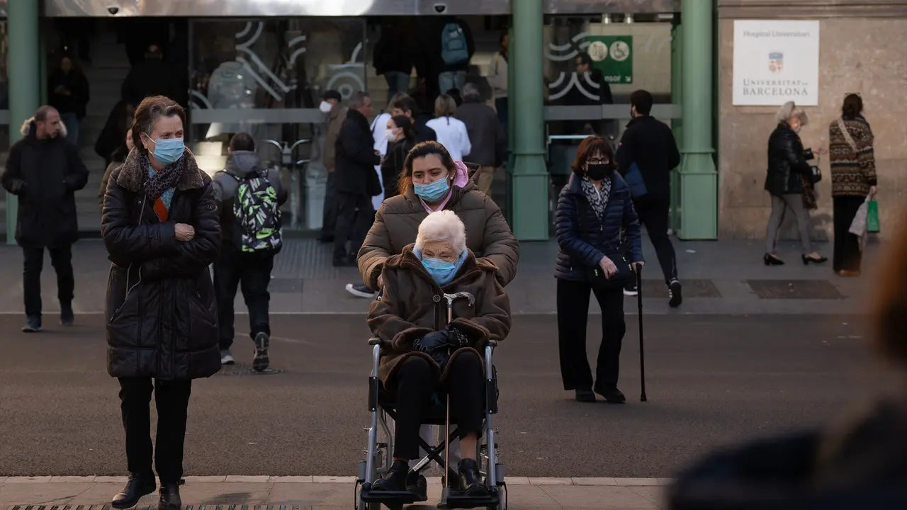 Varias personas con mascarillas en las afueras de un hospital. EP / David Zorrakino