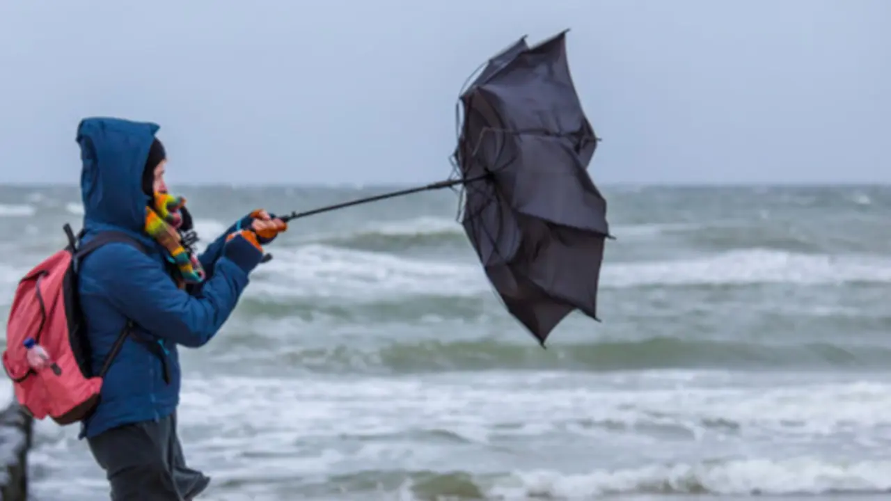 Un hombre intenta controlar su paraguas por la fuerza del viento. / ALERTA