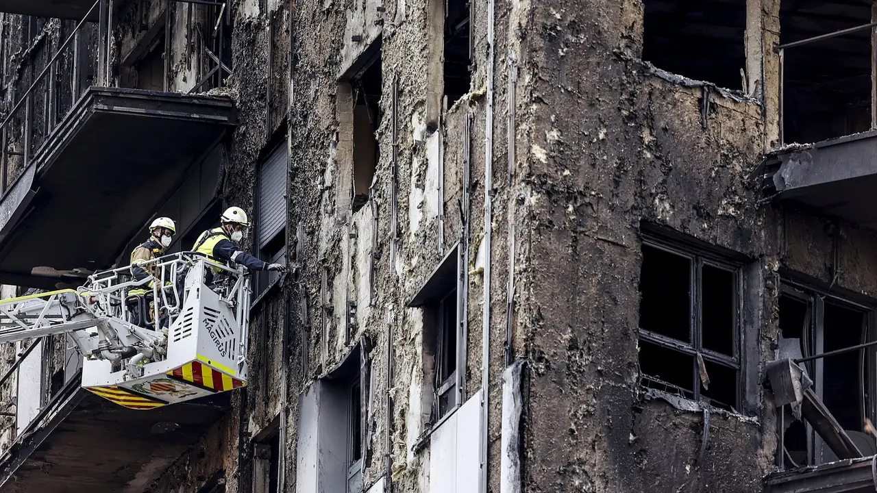 Bomberos en una gr&uacute;a sanean la fachada quemada del edificio en Campanar. EP / Rober Solsona