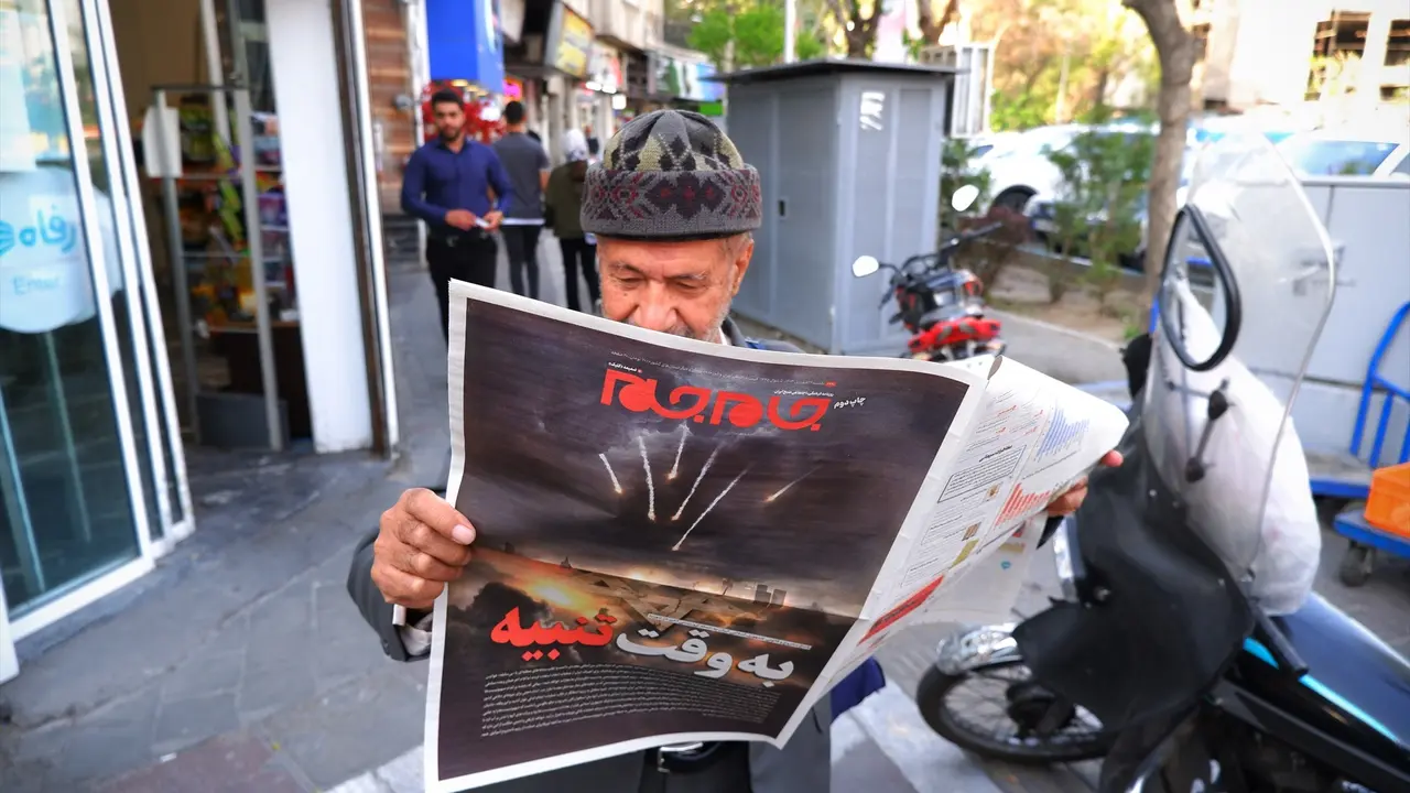 Un hombre en Teher&aacute;n leyendo un peri&oacute;dico con la imagen de unos ataques. EP / Rouzbeh Fouladi