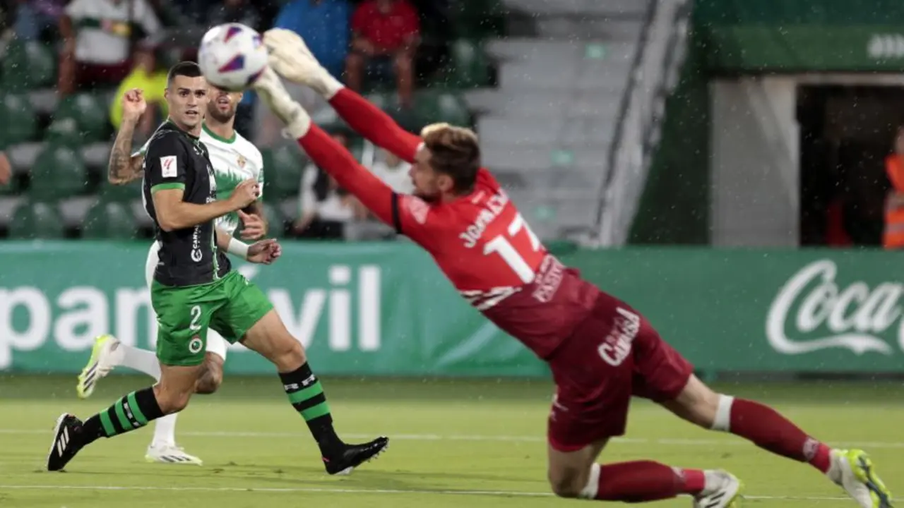 Jokin Ezkieta se estira para alcanzar un bal&oacute;n bajo la atenta mirada de Mantilla en el partido de ida jugado en Elche. / Liga Hypermotion