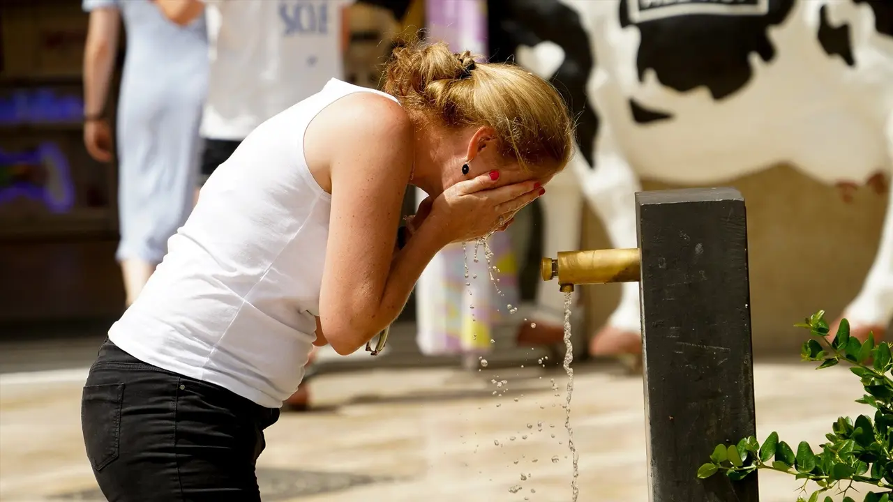 Una mujer se refresca en una fuente. / Archivo