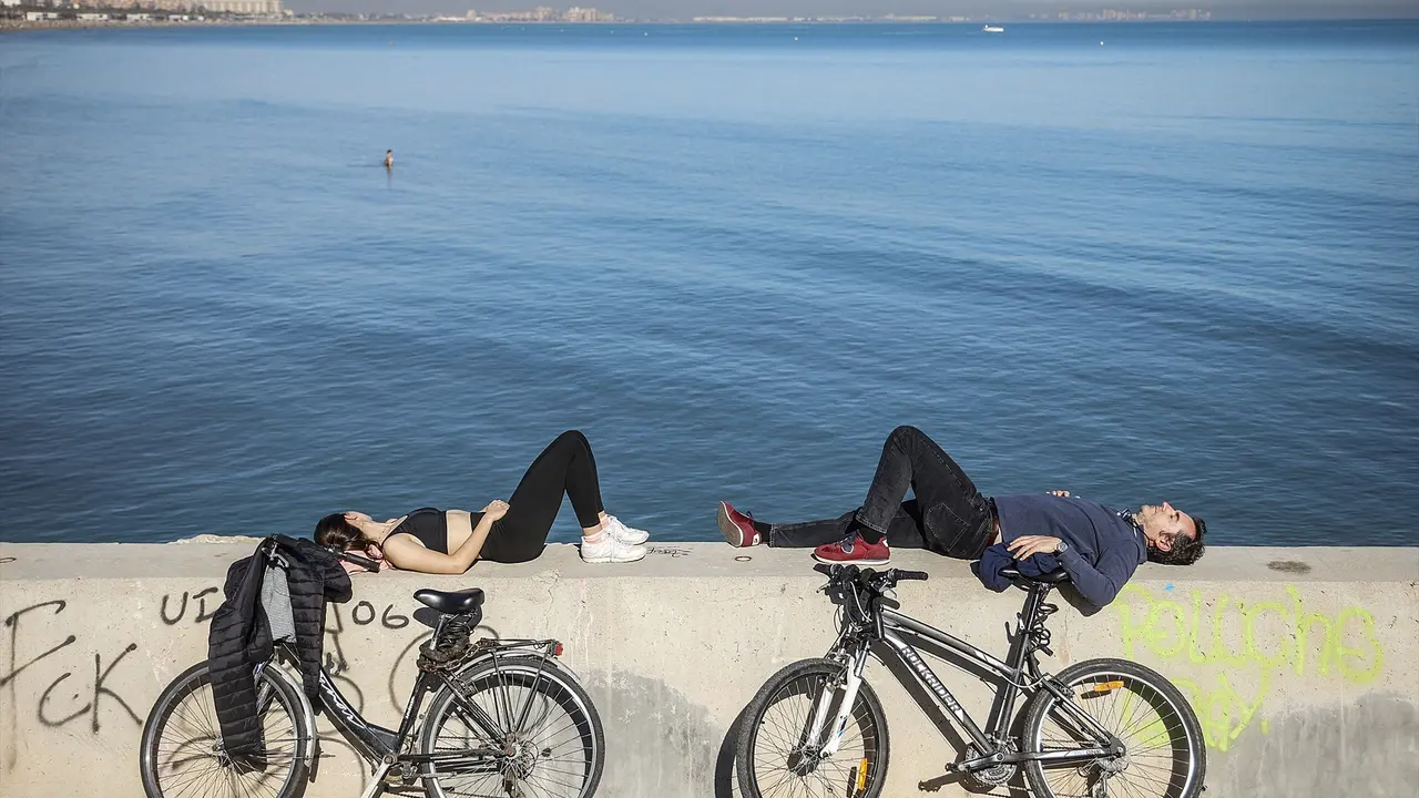 Dos personas tumbadas, frente a la playa de la Malvarrosa. Rober Solsona / Archivo