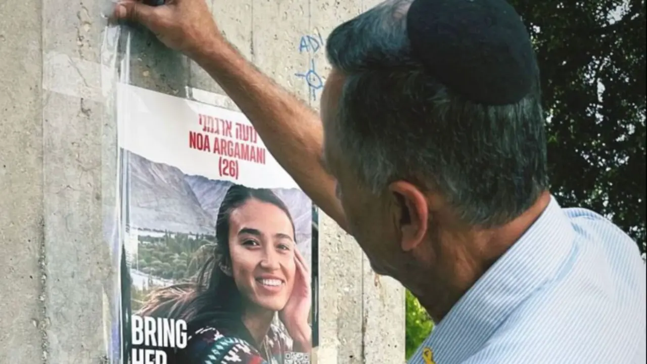 Un padre pega un cartel de su hija raptada por los terroristas de Ham&aacute;s.