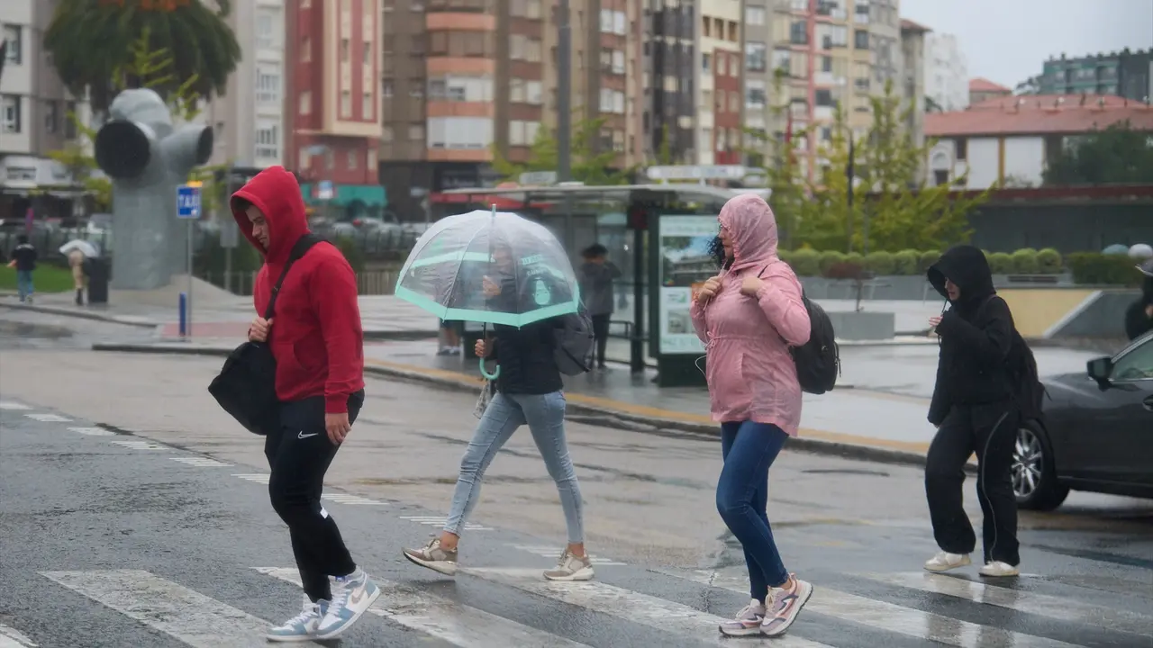 Varias personas se cubren de la lluvia y el viento con paraguas. EP