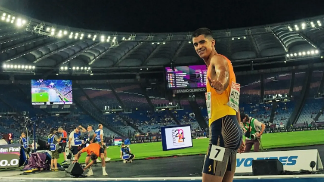 El atleta sonr&iacute;e y saluda tras completar una carrera en el estadio, mostrando su satisfacci&oacute;n y optimismo durante la competici&oacute;n nocturna.
