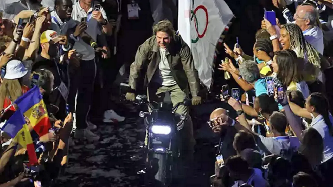 El actor estadounidense Tom Cruise, coge la bandera ol&iacute;mpica subido en una moto. / EP