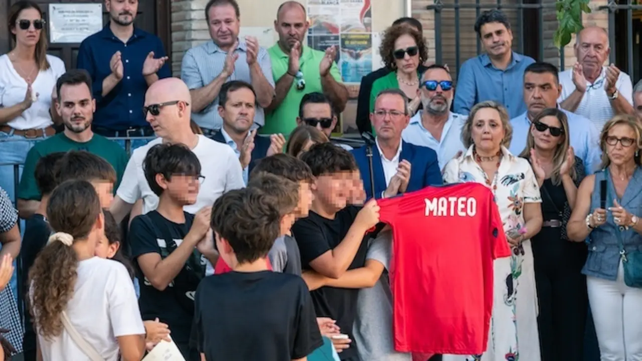 Amigos del ni&ntilde;o asesinado muestran una camiseta con su nombre, durante el minuto de silencio por el asesinato de un menor, en la puerta del Ayuntamiento de Mocej&oacute;n, a 18 de agosto de 2024, en Mocej&oacute;n, Toledo, Castilla-La Mancha (Espa&ntilde;a). El Ayuntamiento de Mocej&oacute;n ha decretado tres d&iacute;as de luto oficial por el asesinato en la ma&ntilde;ana de hoy de un menor de 11 a&ntilde;os, que se encontraba jugando al f&uacute;tbol junto a otros ni&ntilde;os de la localidad en el campo de f&uacute;tbol municipal '&Aacute;ngel Tard&iacute;o' cuando fue agredido con un objeto punzante. leer menos

Firma: Juan Moreno / Europa Press