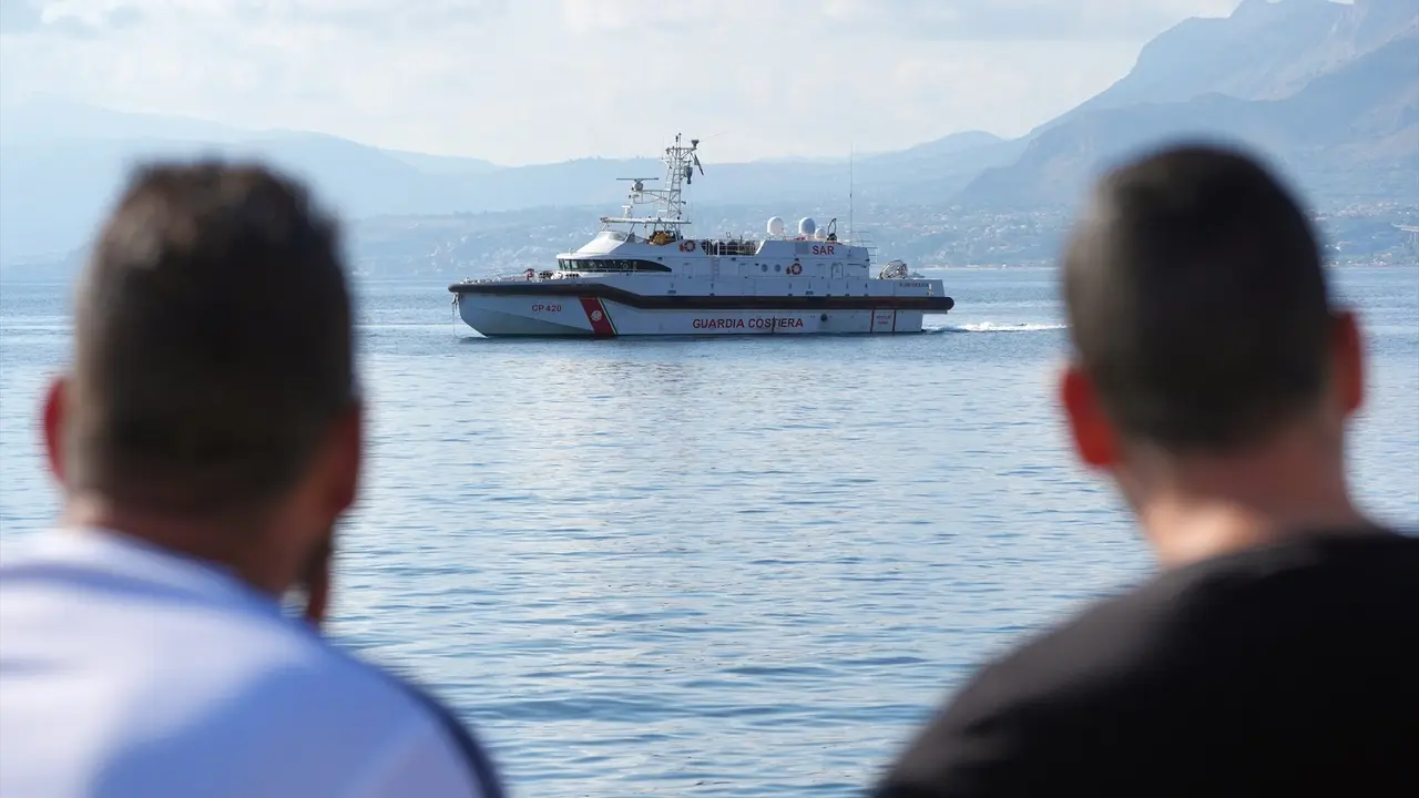 Dos personas miran el barco de la Guardia Costera que trabaja en las labores de rescate. Jonathan Brady