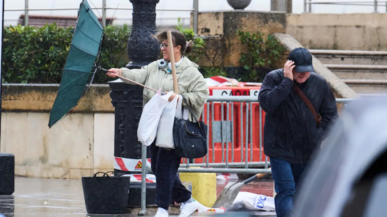 Varias personas tratan de cubrirse de la lluvia y el viento, en Santander. / EP