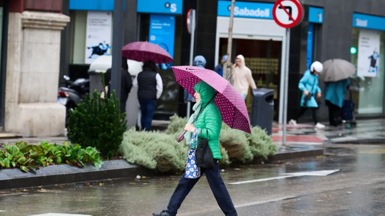 Una persona se cubre de la lluvia y el viento con paraguas en  Santander. / Juanma Serrano