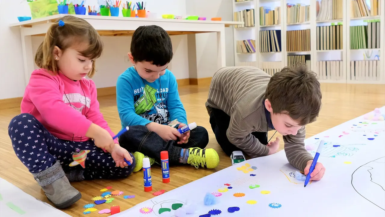 Tres ni&ntilde;os pintando en una guarder&iacute;a. / Alerta
