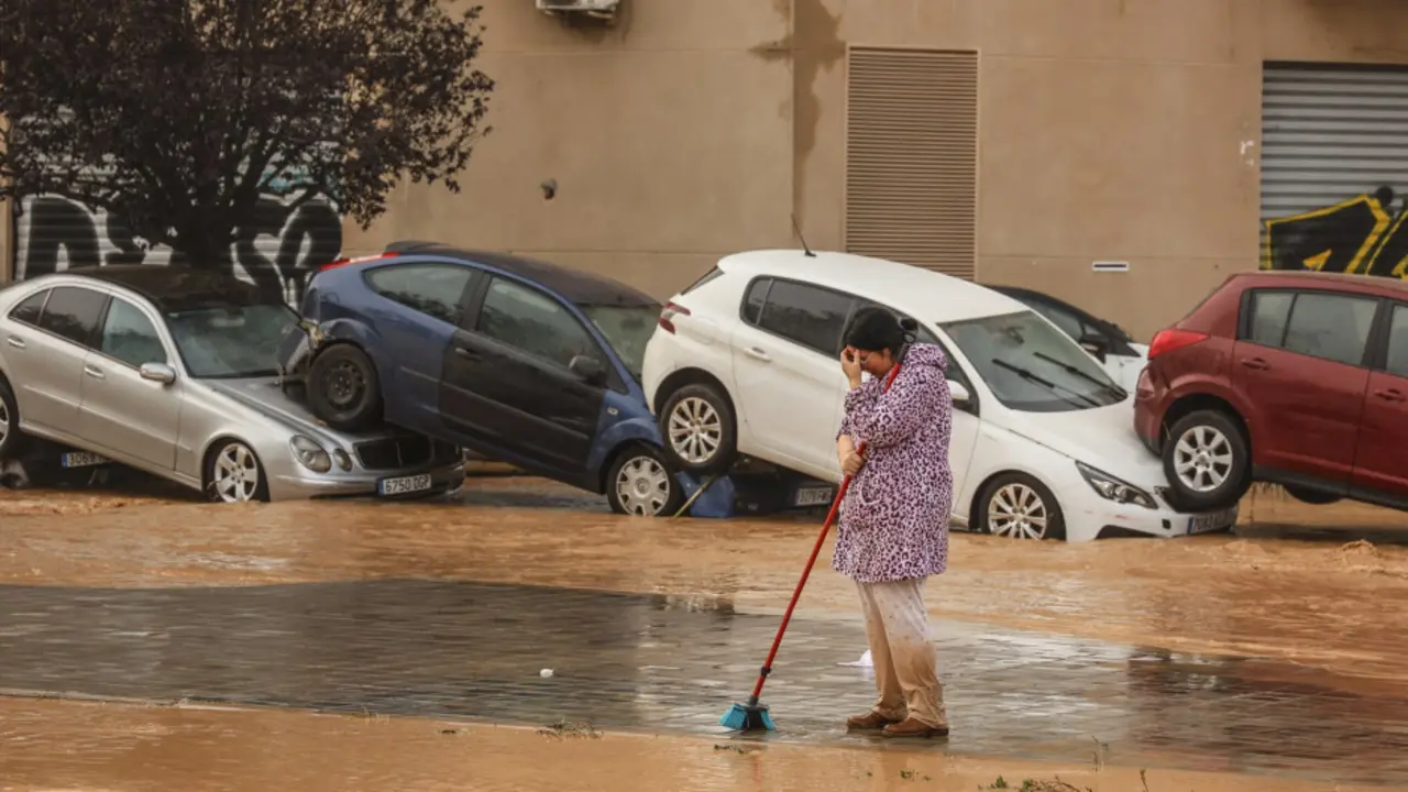 Una mujer realiza labores de limpieza junto a veh&iacute;culos destrozados tras el paso de la DANA por el barrio de La Torre de ValenciaEuropa Press