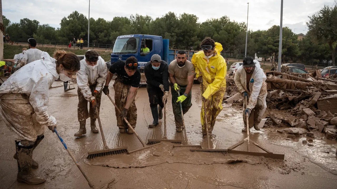 Varias personas retiran barro con cepillos en Alfafar. / Mat&iacute;as Chiofalo