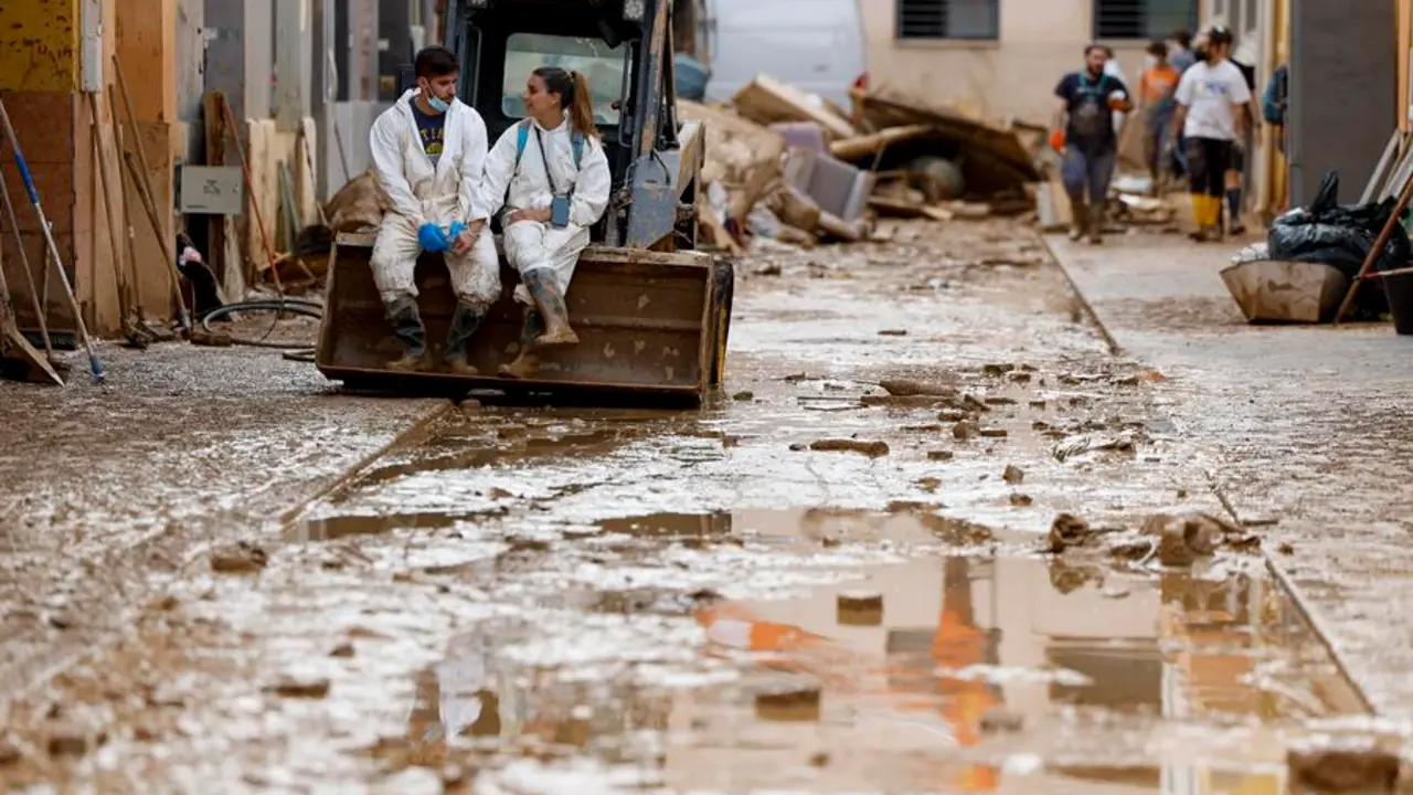 PAIPORTA (VALENCIA), 09/11/2024.- Una pareja de voluntarios se toman un descanso en una calle en Paiporta este s&aacute;bado, que afronta el fin de semana con el reto de avanzar en la recuperaci&oacute;n de la zona cero de la dana que asol&oacute; Valencia hace once d&iacute;as y de encontrar m&aacute;s personas desaparecidas, todo ello en medio de un 'ej&eacute;rcito' de voluntarios, una ingente cantidad de ayuda solidaria y el eco incesante de la pol&eacute;mica pol&iacute;tica en torno a la gesti&oacute;n de aquel fat&iacute;dico 29 de octubre.- EFE/ Jorge Zapata